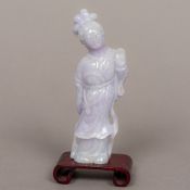 A Chinese lavender jade figural carving formed as Guanyin Together with a scrolled wood base.