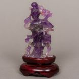 A Chinese amethyst carving of Guanyin Modelled holding a lantern and flowers,