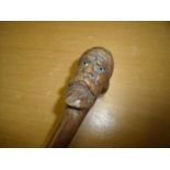 19th C folk art carved walking stick, the handle in the form of a Turks head with inset glass