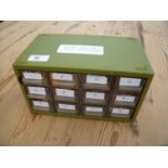 Twelve drawer green plastic cabinet containing various repair parts for watches including various