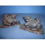 Pair of oriental carved wood figures of men upon the backs of water buffalo with glass inset eyes