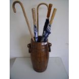 Oak barrel shaped stick stand with two ring handles and a selection of walking sticks and umbrellas