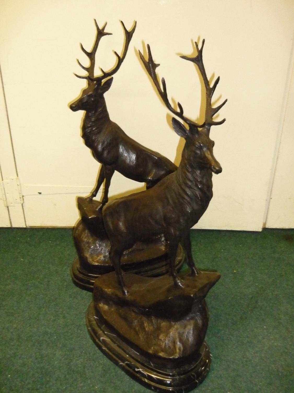 A large pair of bronze stags on rocky outcrops mounted on oval stepped marble bases (72cm high)