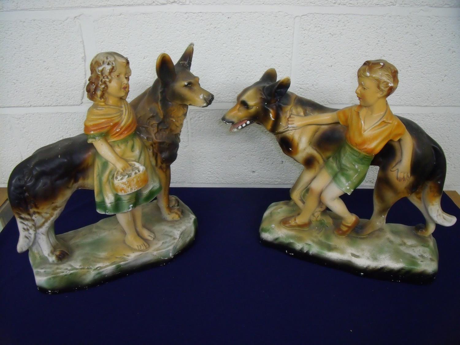 Pair of large mid 20th C painted plaster figures of a boy and a girl with Alsatians (approx. 42cm