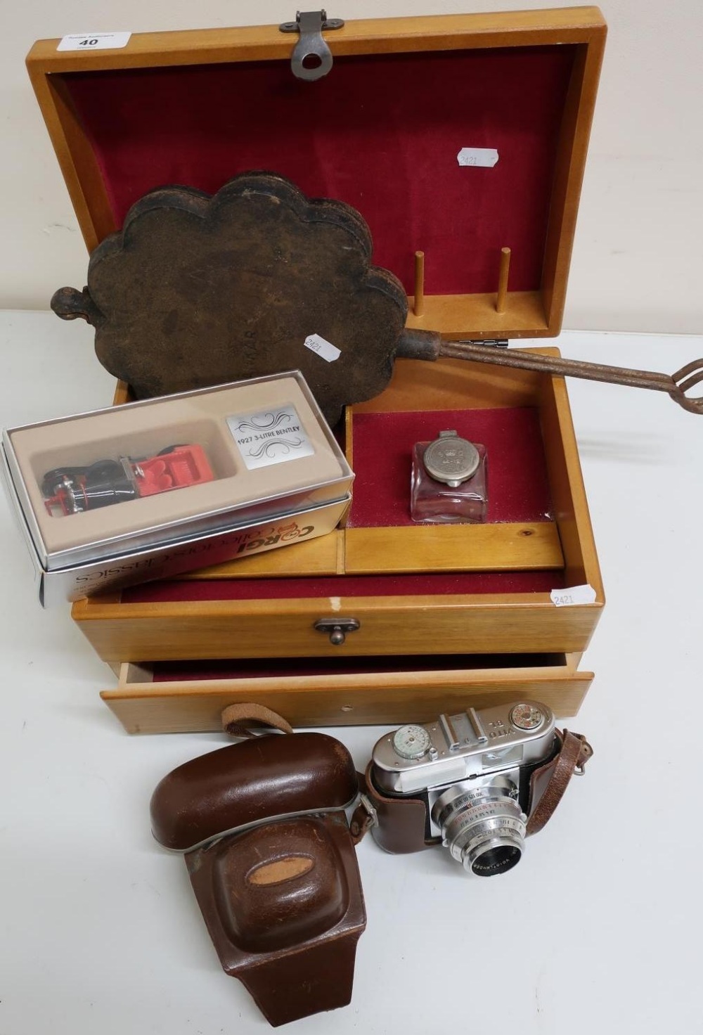 Wooden storage box with vintage camera, boxed Corgi car, inkwell and cast metal waffle maker