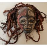 Carved African tribal style face mask with coloured highlighted detail on hessian ropework hair