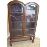Circa 1930s oak double arch top cabinet enclosed by two glazed doors, on turned and bulbous supports