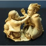 19th C finely carved Japanese ivory group of eldery gentleman being dressed by a lady, both in