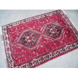 20th C Bokhara red ground rug with two central medallions and floral border (157cm x 103cm)