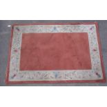 Chinese embossed washed woollen rug, terracotta ground with floral pattern border (180cm x 122cm)