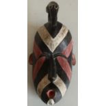 Unusual carved tribal style face mask with white, black and red stripe detail, crested with a figure