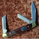 Buck three bladed pocket knife with two piece wooden grips and brass mounts