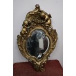 Gilt plaster bevelled edge wall mirror crested with two Cupids (90cm x 54cm)