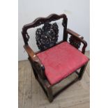 Carved Chinese hardwood armchair with broad seat, elaborately carved back and arm supports, with