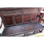 19th C large oak settle style bench with two carved panels above four panels to the back, on