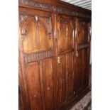 Large early 20th C oak triple door combination wardrobe with carved and panelled details, with