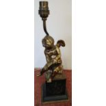 Table lamp in the form of a gilt metal cherub scribing a book, on raised black slate and gilt