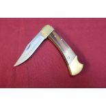 Boxed Buck USA pocket knife with 3 1/4 inch folding blade, two piece wooden grips and brass mounts