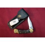 Buck Knives pocket knife with folding blade, two piece wooden and brass grips with leather belt