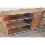 Ercol light elm side cabinet with two sliding glazed doors enclosing two shelves, flanked by