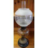 Late 19th C oil lamp with clear glass reservoir, circular tapering embossed brass base on black