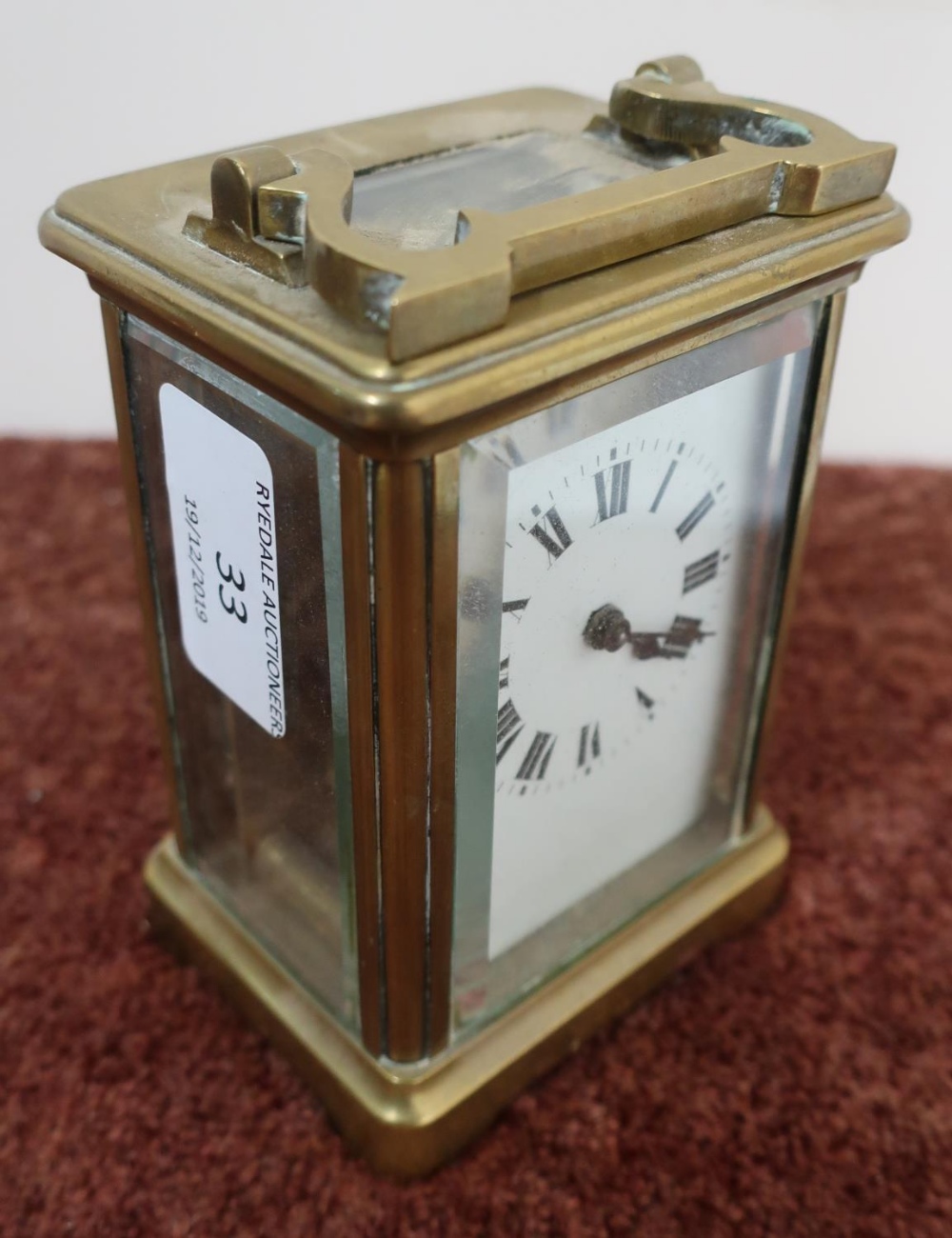 Brass cased French made carriage clock with white enamel dial, complete with key and swing handle (