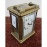 Brass cased French made carriage clock with white enamel dial, complete with key and swing handle (