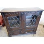 Oak cabinet enclosed by two lead glazed doors above two further cupboard doors (111cm x 33cm x 99cm)