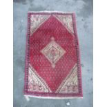 Traditional Middle Eastern red ground patterned rug with central beige medallion and beige ground