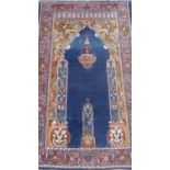 20th C Middle Eastern rug, blue ground stylised doorway motif surrounded by floral pattern border (