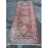 Traditional Middle Eastern red ground runner with five central diamond pattern medallions and