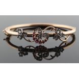An attractive late Victorian unmarked yellow gold ruby & diamond hinged bangle, with scrolling