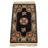 Property of a lady - a Chinese hand knotted rug with floral pattern on a black ground, 60 by