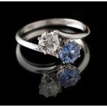 A platinum sapphire & diamond two stone crossover ring, the clear cornflower blue sapphire