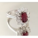 An 18ct white gold ruby & diamond floral cluster ring, the oval cushion cut ruby weighing