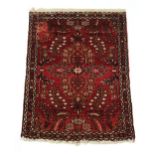 A Tabriz woollen hand-made rug with red ground, 40 by 29ins. (102 by 74cms.) (see illustration).