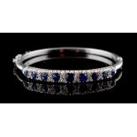 A late Victorian sapphire & diamond hinged bangle, set with nine graduated oval cut sapphires