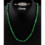 A Chinese apple green jadeite bead necklace, the seventy-five individually strung uniform beads each