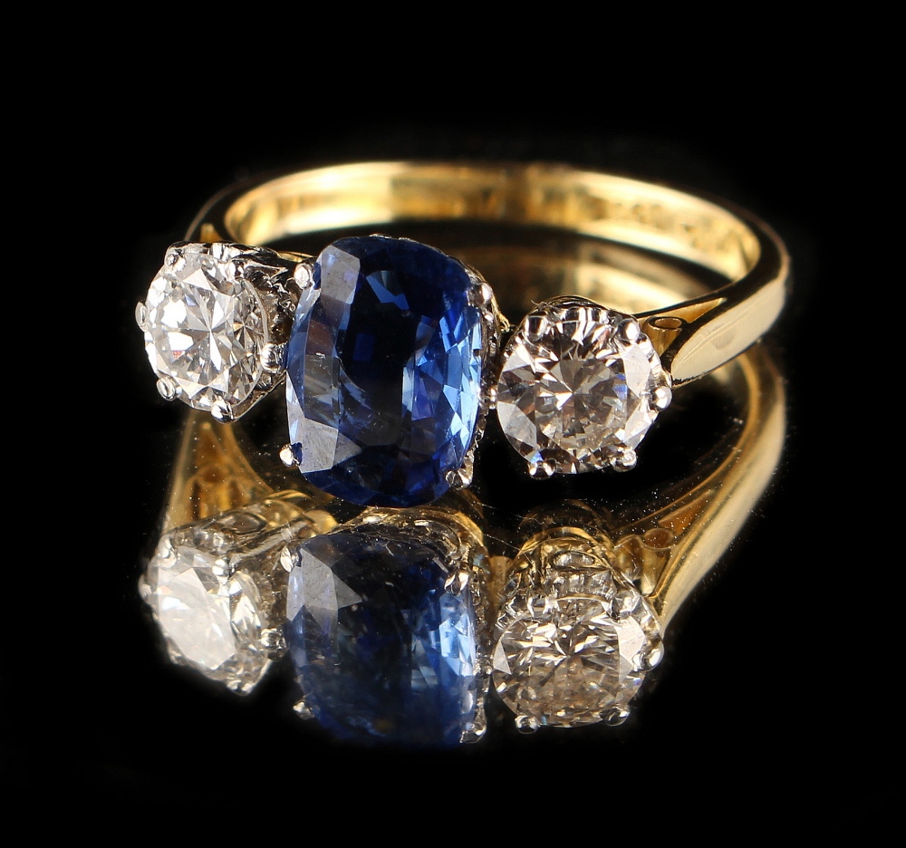 An 18ct yellow gold sapphire & diamond three stone ring, the central cushion cut sapphire weighing