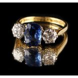 An 18ct yellow gold sapphire & diamond three stone ring, the central cushion cut sapphire weighing