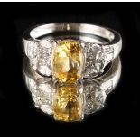 A yellow sapphire & diamond ring, the central cushion cut yellow sapphire of clear vibrant