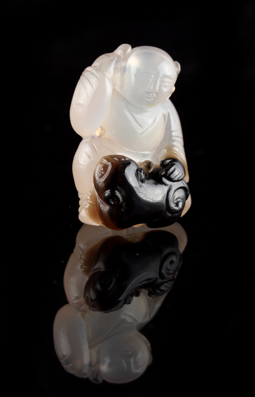 A Chinese carved agate figure of a seated boy with a cub at his feet, 1.35ins. (3.4cms.) high (see - Image 2 of 2