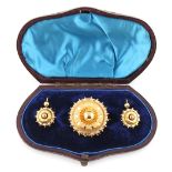 A Victorian unmarked yellow metal circular brooch with earrings en suite, each with diamond