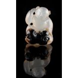 A Chinese carved agate figure of a seated boy with a cub at his feet, 1.35ins. (3.4cms.) high (see