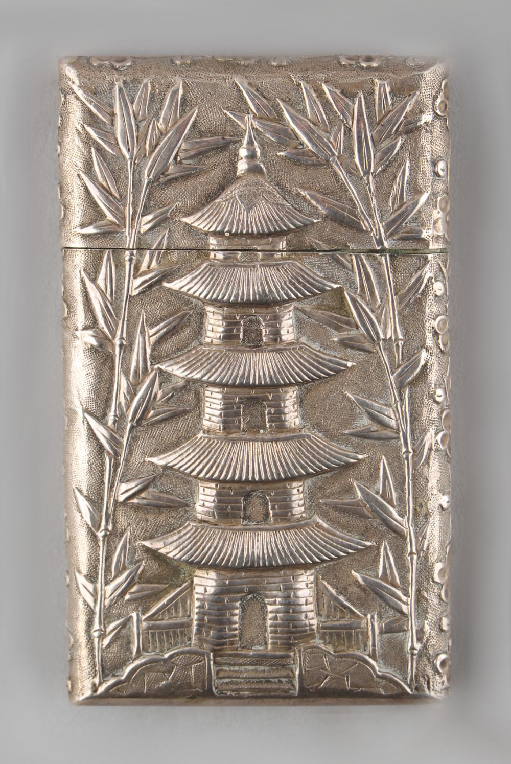 A late 19th / early 20th century Chinese silver card case, decorated in relief with a pagoda &