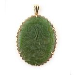 Property of a lady - a 9ct gold oval framed Chinese jadeite pendant, carved with a dragon, 50mm long