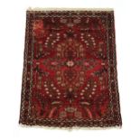 A Tabriz woollen hand-made rug with red ground, 40 by 29ins. (102 by 74cms.)