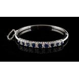 A sapphire & diamond hinged bangle, the nine graduated oval cut sapphires weighing a total of