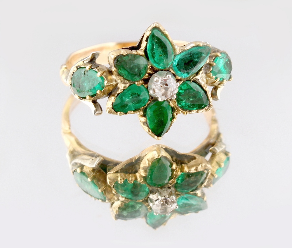 A Georgian emerald & diamond flowerhead ring, with eight pear shaped emeralds flanking a small