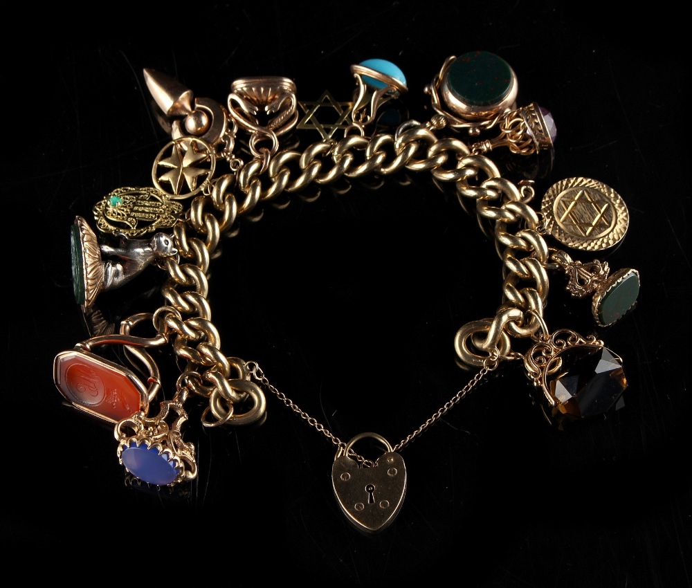 Property of a lady - a 9ct gold charm bracelet hung with various charms, intaglio seals & fobs,